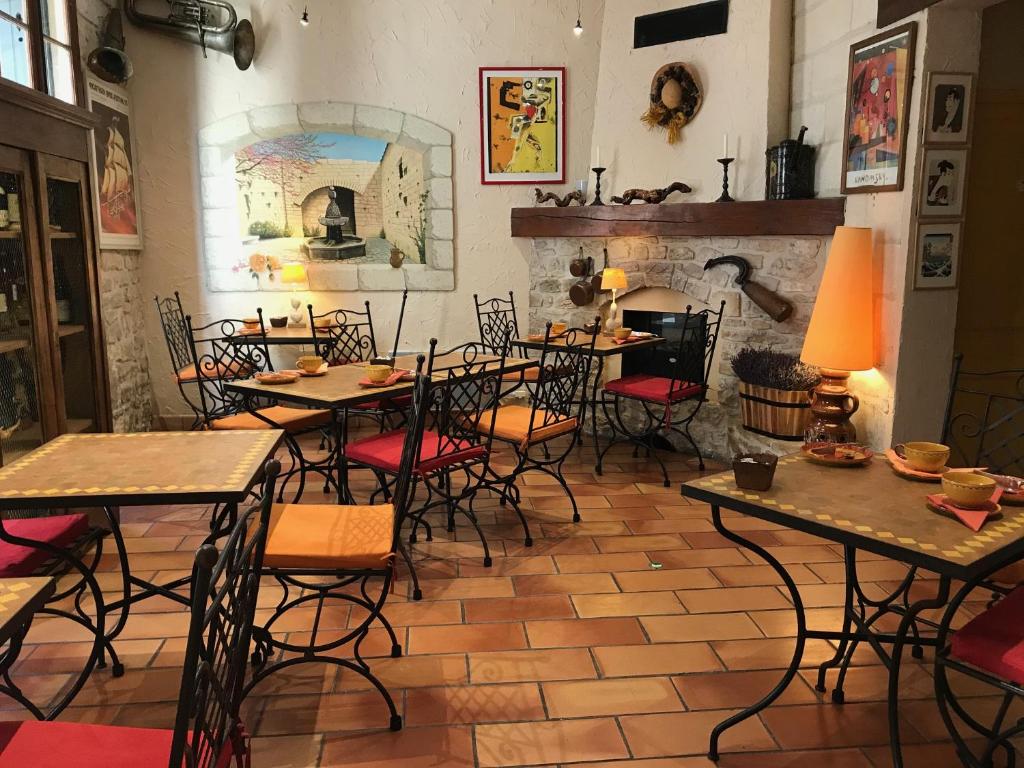 アヴィニョンにあるオテル ル コルベールのテーブルと椅子、暖炉のあるレストラン
