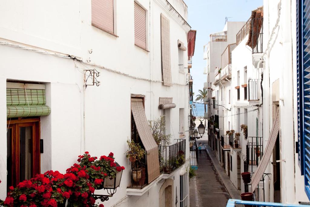 an alley with flowers on the side of buildings at Blaumar in Sitges