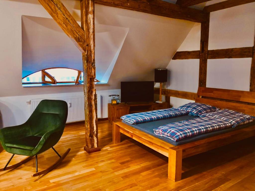 ein Schlafzimmer mit einem Bett und einem grünen Stuhl in der Unterkunft Historisches Ambiente mitten im Zentrum in Eberswalde-Finow