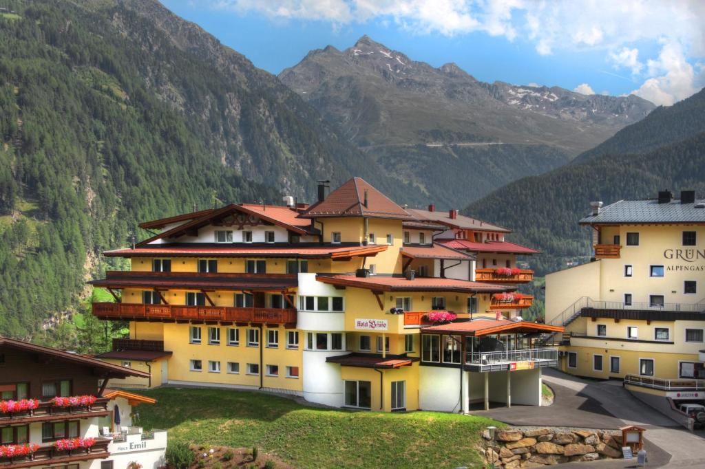 um grupo de edifícios com montanhas ao fundo em Hotel Bruno em Sölden