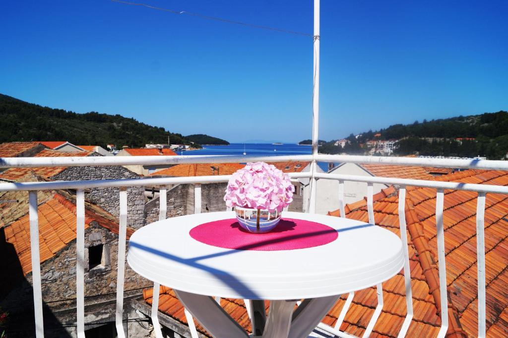 une table blanche avec des fleurs roses sur un balcon dans l'établissement Art Apartment, à Vela Luka