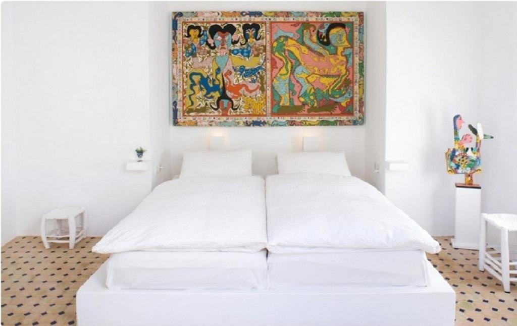 a bedroom with two beds and a painting on the wall at Unique Architect's House in Essaouira