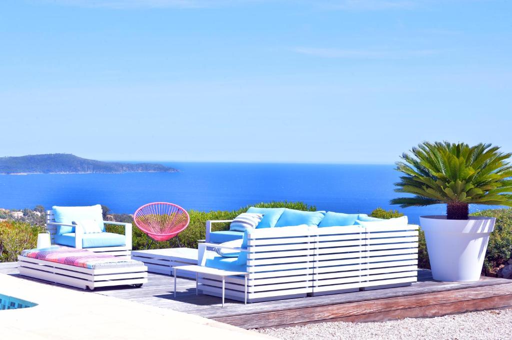 a patio with blue and white furniture and the ocean at VILLA JUCANOS - Vue mer panoramique Golfe de St-Tropez in Cavalaire-sur-Mer