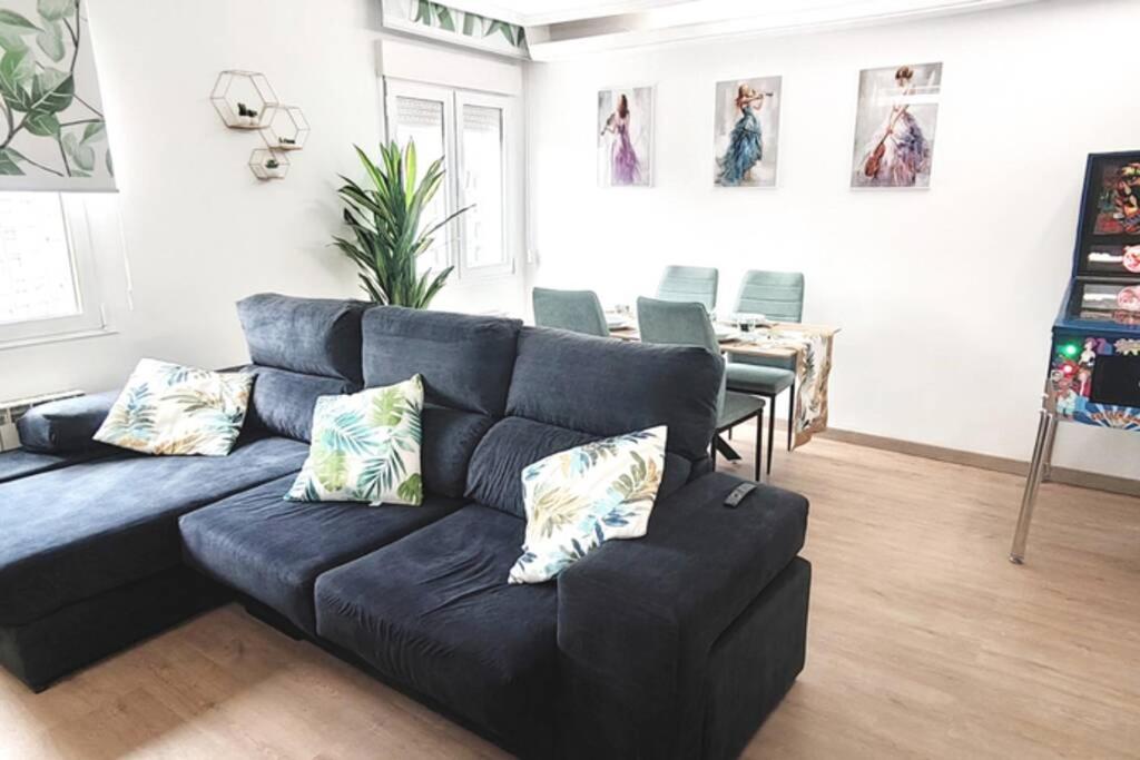 uma sala de estar com um sofá preto com almofadas em Estrenar! Con PINBALL + 8 min ayto + 2 habs 1.50 em Oviedo