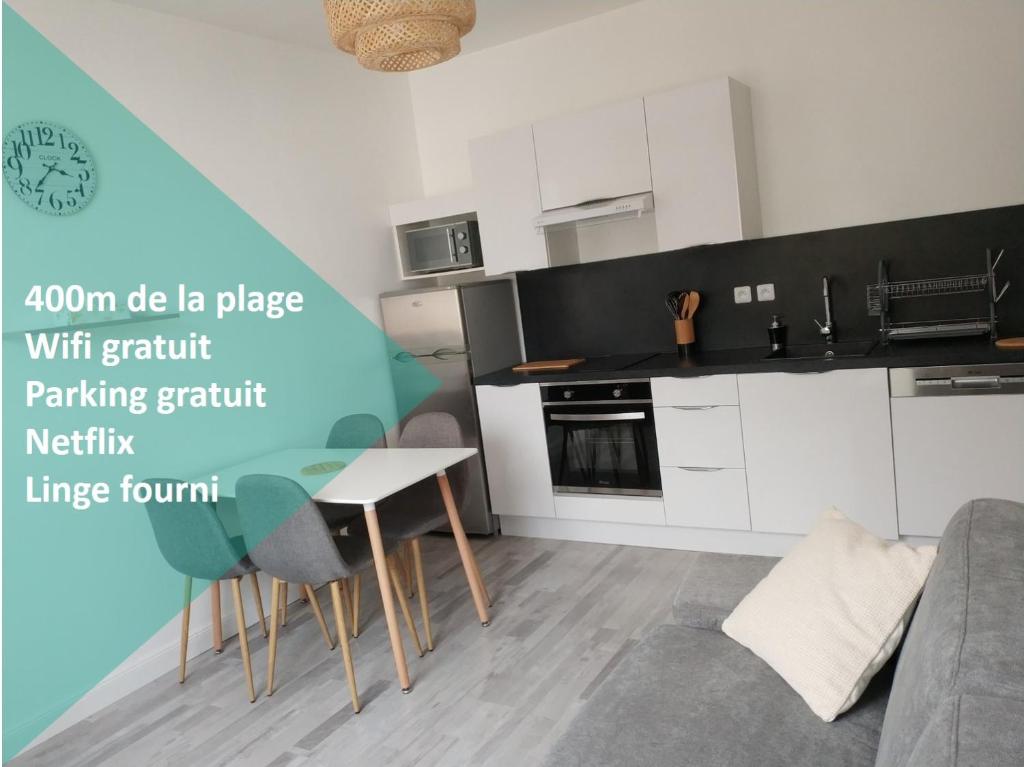 a kitchen with white cabinets and a table and chairs at L'Appartement du Veillon in Talmont