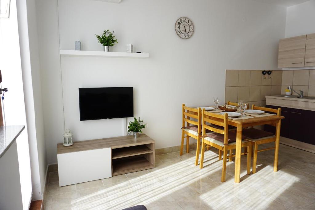 a kitchen and dining room with a table and a television at Apartment Jelena in Fažana
