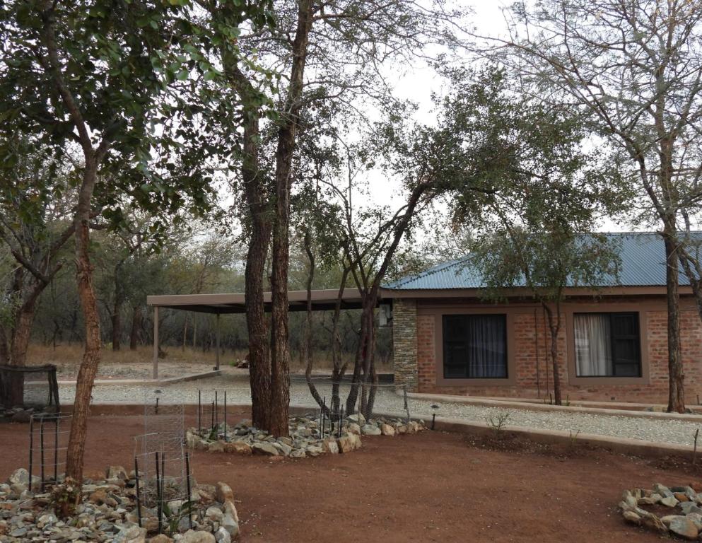 a brick house with a tree in front of it at Locust Retreat Immaculate 2bedroom cottage in Marloth Park