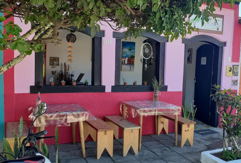 un restaurante con 2 mesas y una pared rosa en Pousada Berimbau, en Arraial d'Ajuda