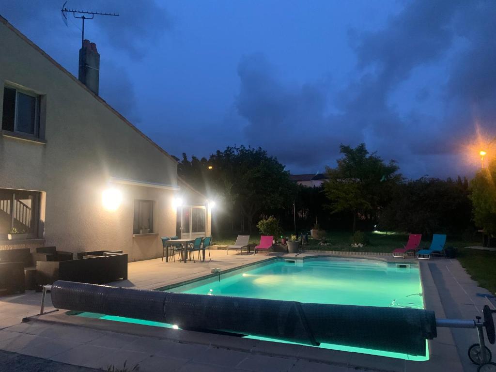 a swimming pool in front of a house at night at Chez Cathy in LʼHoumeau