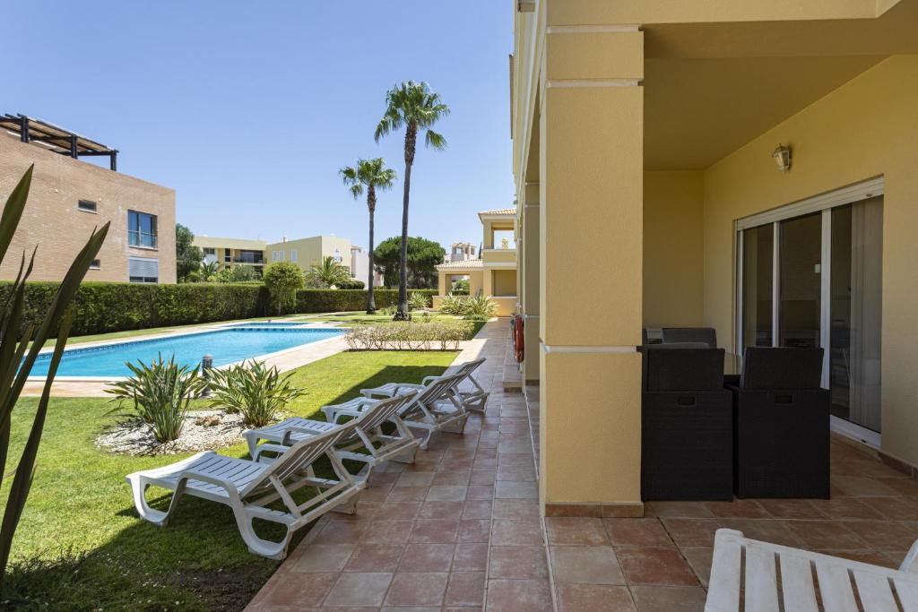 a row of lounge chairs next to a swimming pool at Real Alegria - Terrace with pool - Vilamoura in Vilamoura