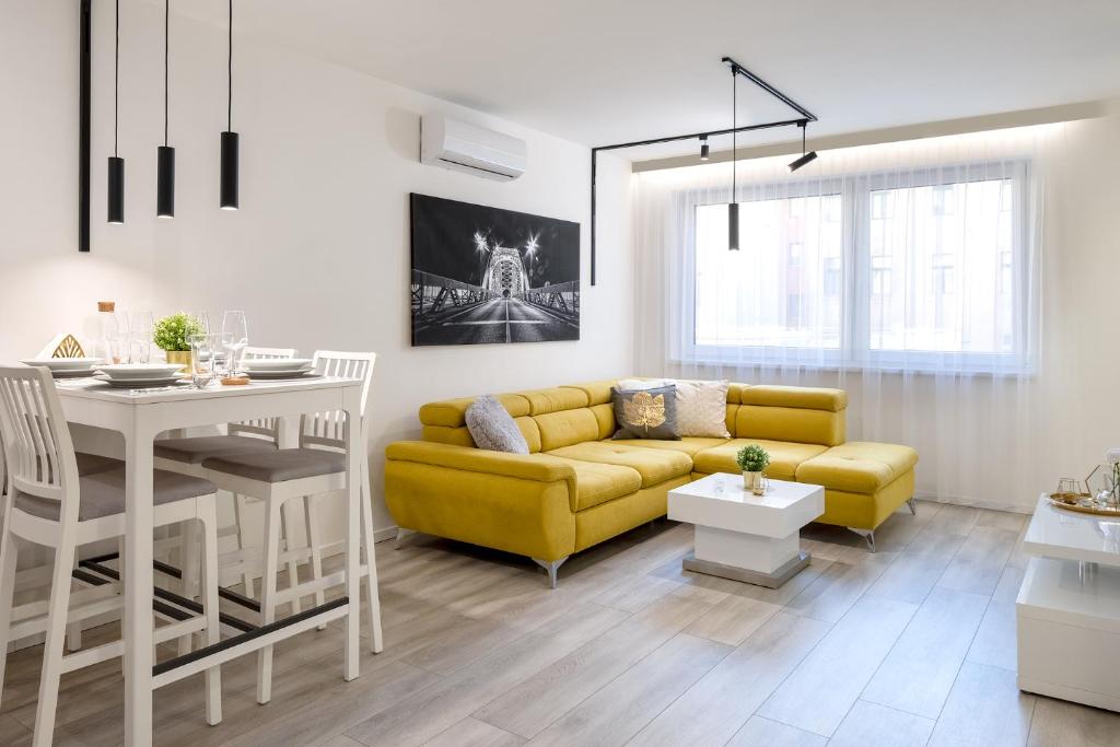 a living room with a yellow couch and a table at Divat Apartments - Central Smart Homes in Győr