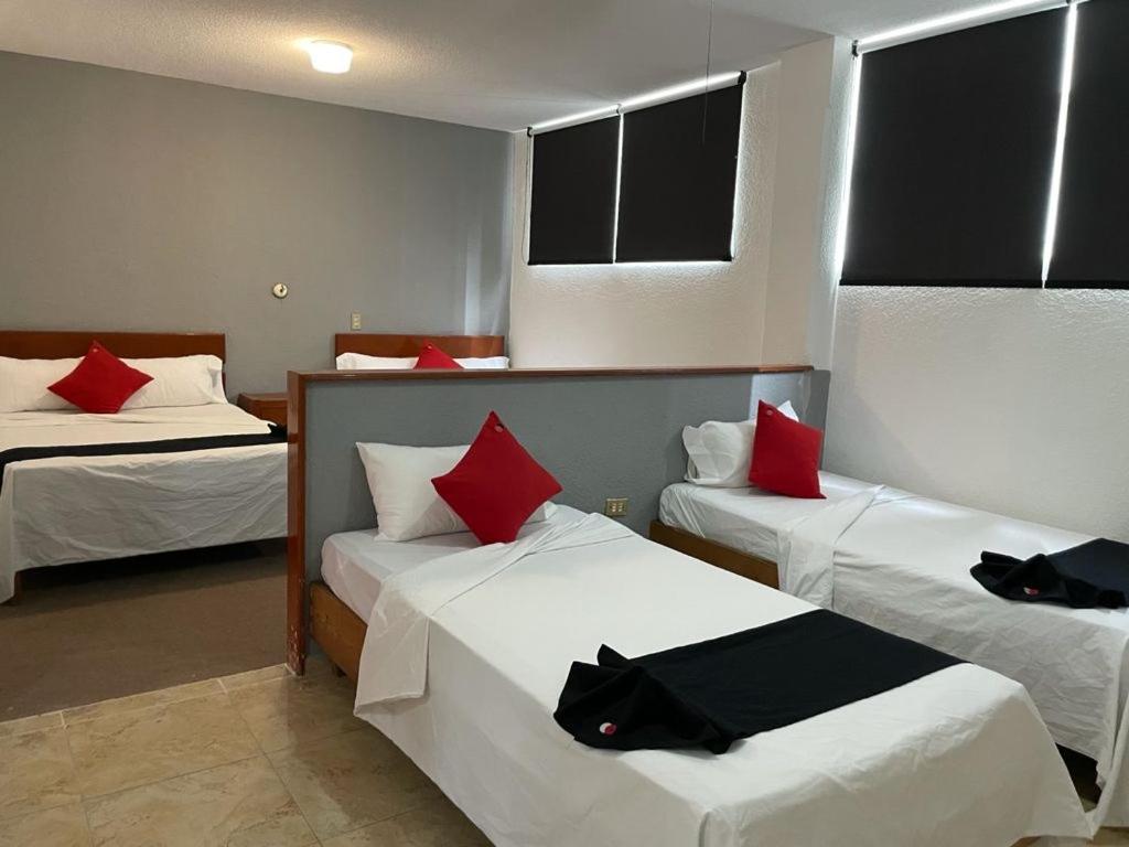 Habitación de hotel con 2 camas con almohadas rojas en HOTEL SiCILIA iTALIA, en Aguascalientes