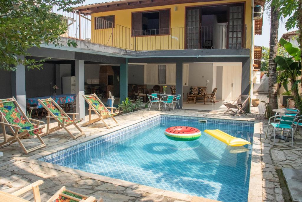 a swimming pool with chairs and a house at Hostel Morada do sol Paraty in Paraty
