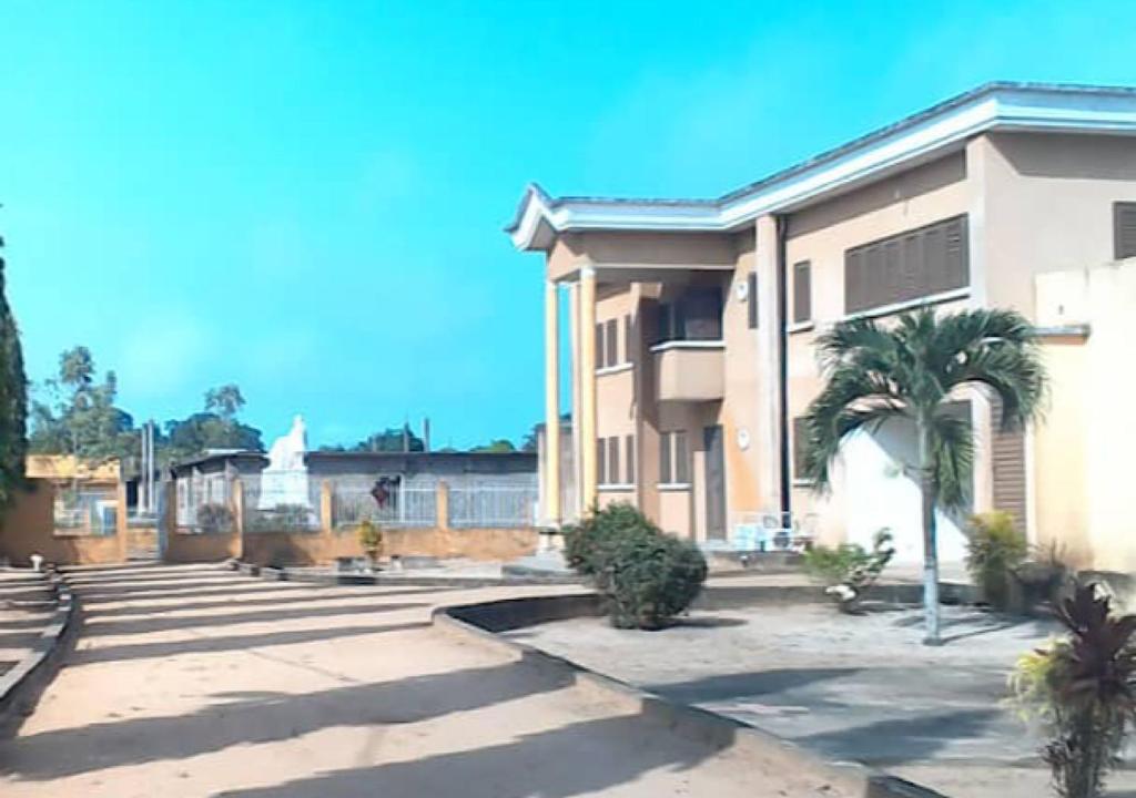 un edificio con una palmera delante de él en Villa CB village Aby, en Aboisso