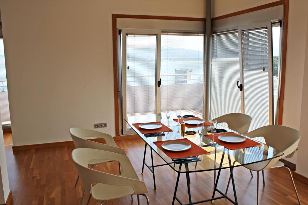 een eetkamer met een glazen tafel en stoelen bij Precioso apartamento, espectaculares vistas. in Cangas de Morrazo