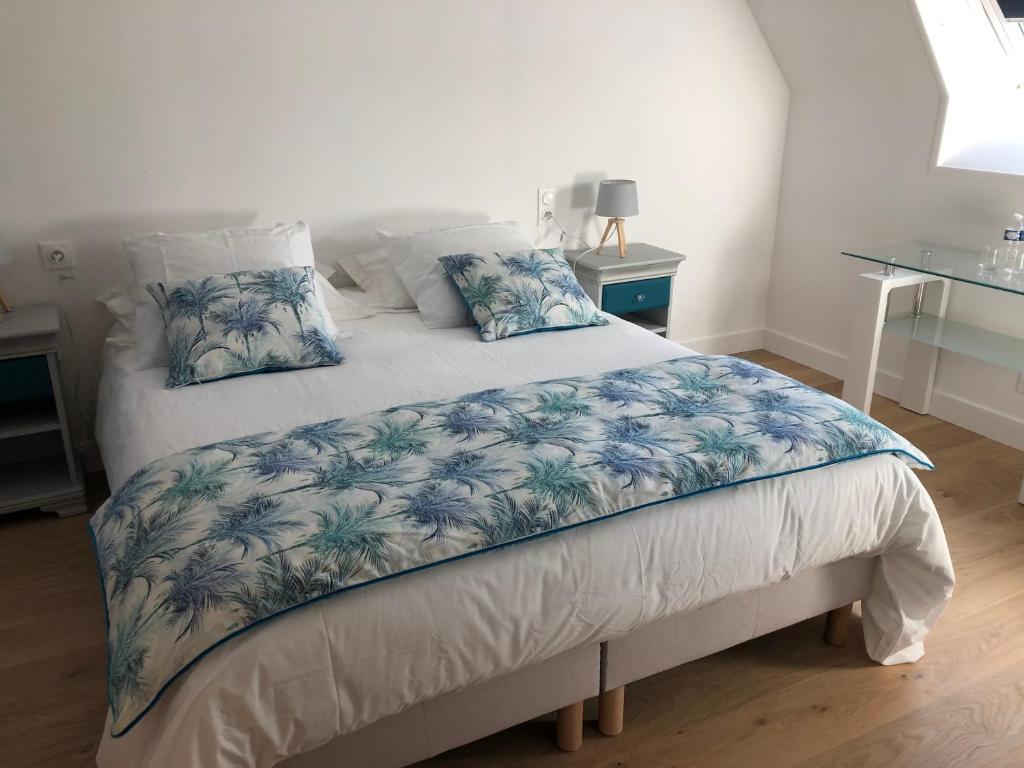 Un dormitorio con una cama con sábanas y almohadas azules y blancas en chambre d'hôtes Le Domaine de la Vallée en Saint-Martin-de-Varreville