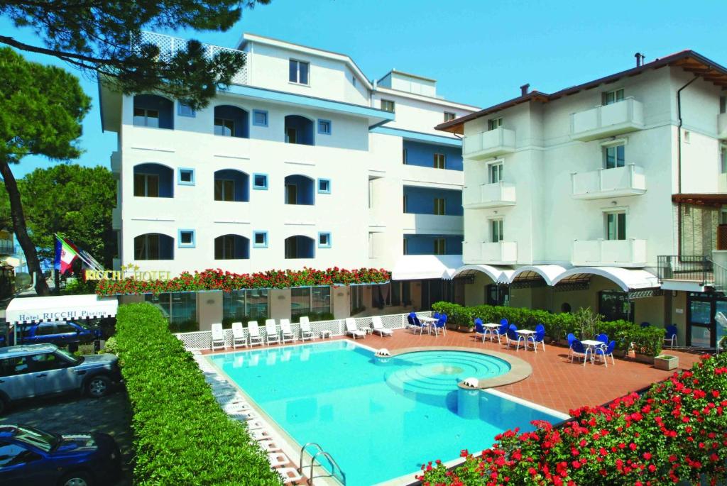 un hotel con piscina di fronte a un edificio di Hotel Ricchi a Rimini
