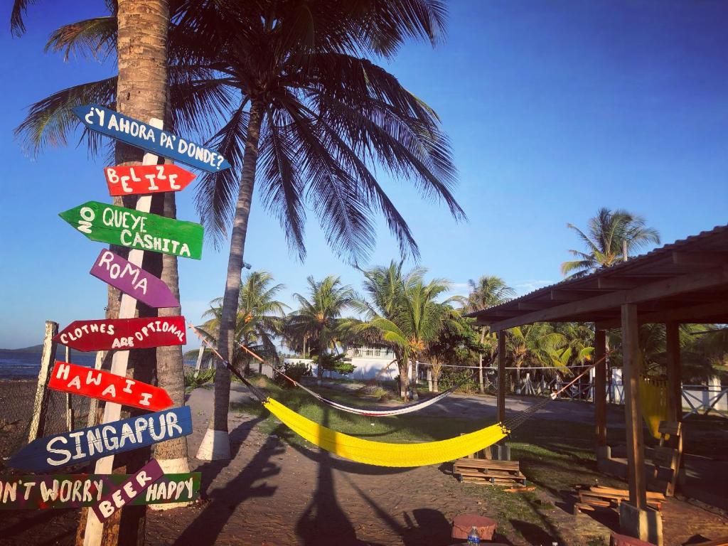 Un mucchio di cartelli su un palo vicino a una spiaggia di Hostal Rudy's Beach a Puerto Cortés