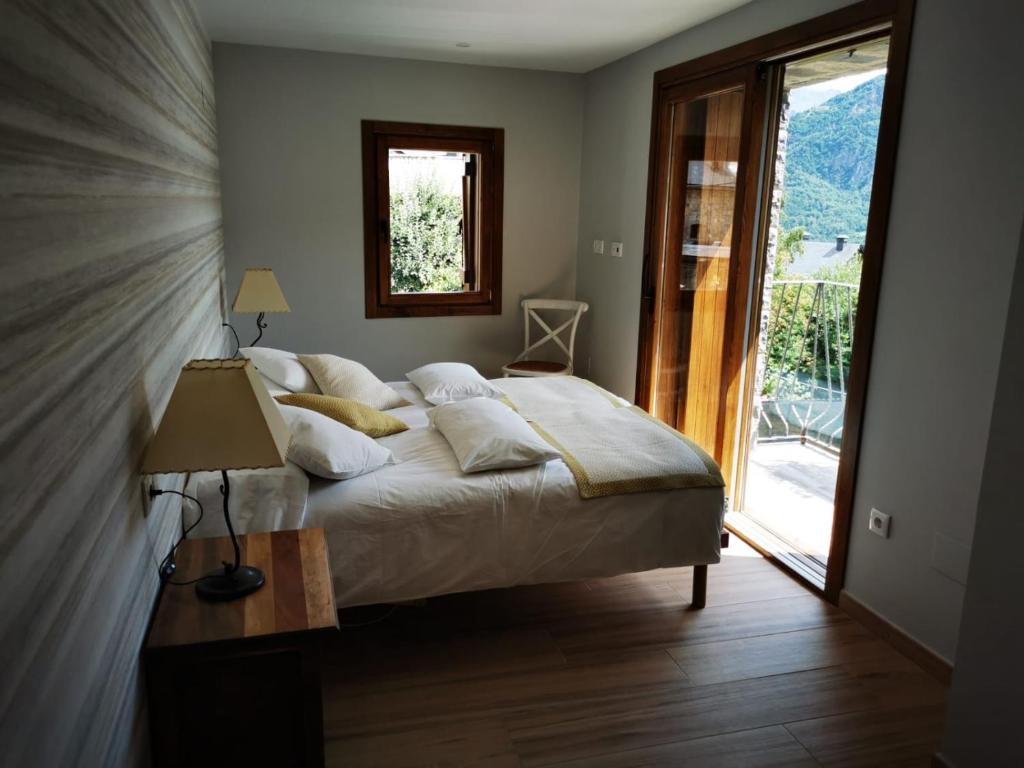 a bedroom with a bed and a large window at La Borda de Jaime in Piedrafita de Jaca