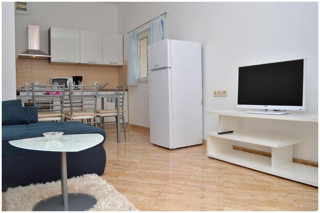 a living room with a couch and a tv and a kitchen at Apartments Luciano in Seget Vranjica