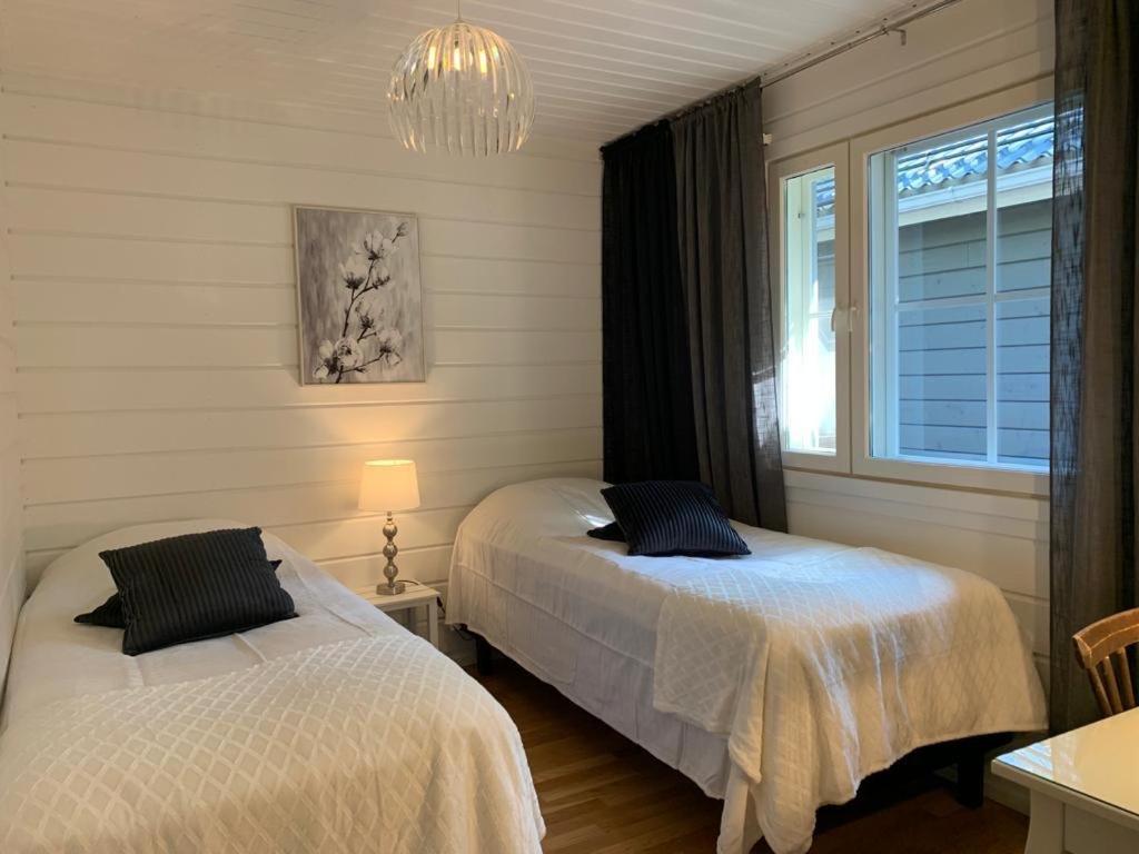 a bedroom with two beds and a window and a chandelier at Elegant villa on the shore of Lake Saimaa in Lappeenranta