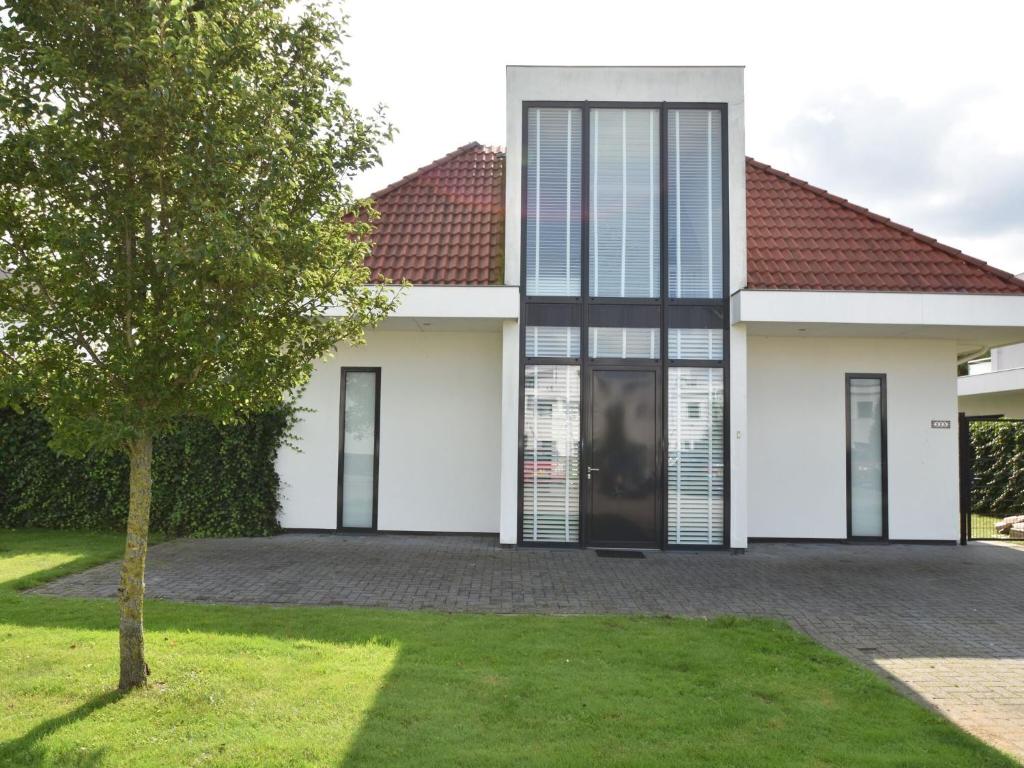 a white house with a red roof at Holiday Home in Zeewolde with Jetty next to golf course in Zeewolde