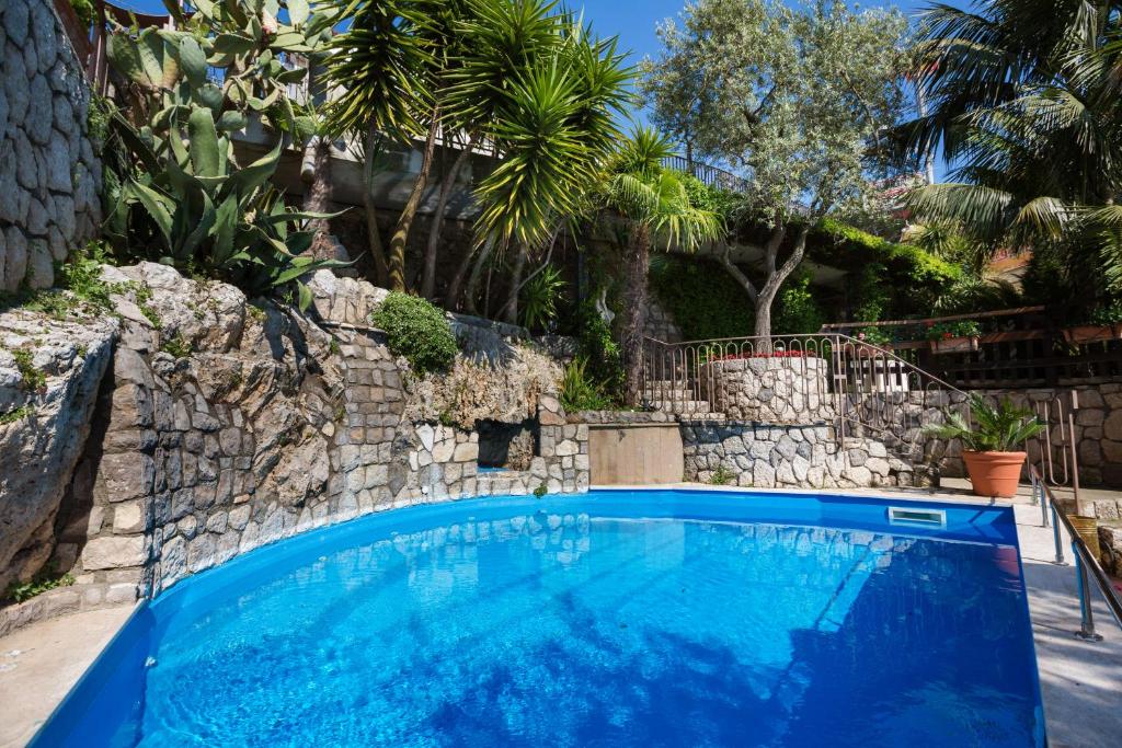 une grande piscine bleue avec un mur en pierre dans l'établissement L'Ulivo Resort, à Vico Equense