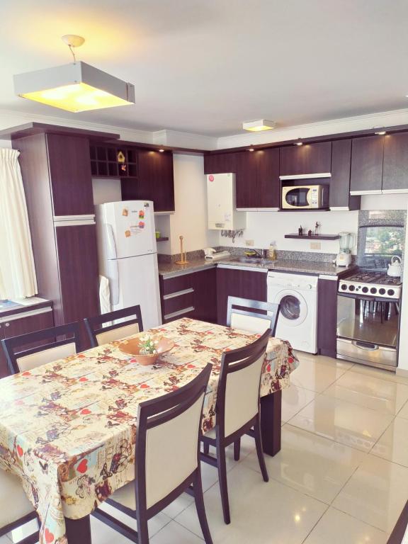 cocina con mesa y sillas y cocina con nevera en Departamento Edificio Manhattan 7mo piso en Villa Carlos Paz