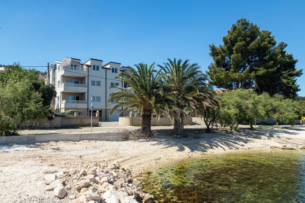 a building on the beach with palm trees at Apartments Janja in Trogir