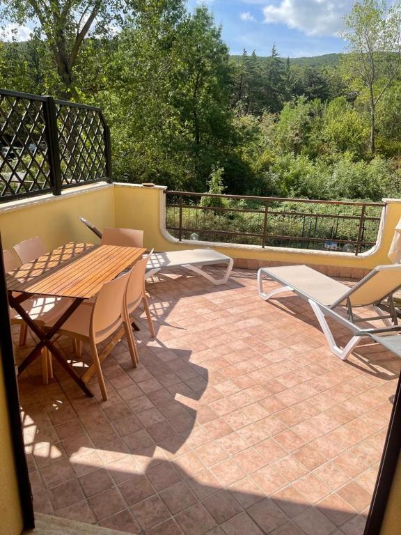 patio z drewnianym stołem i krzesłami na balkonie w obiekcie Villa Terrena w mieście Bagni San Filippo