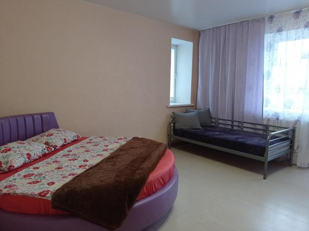 a bedroom with a bed and a couch and a window at 1к. Апартаменты НСК , на пр.Карла Маркса 11 in Novosibirsk