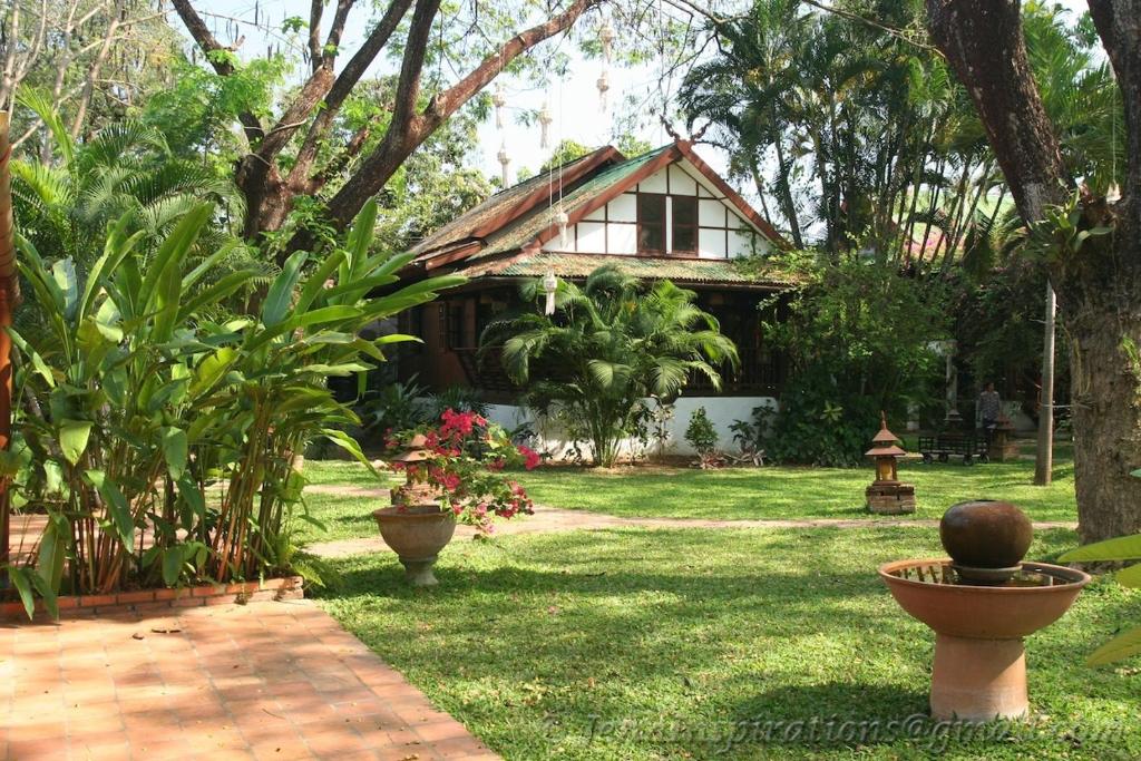 a house with a yard with plants and a pathway at Secret Garden Chiangmai in San Kamphaeng