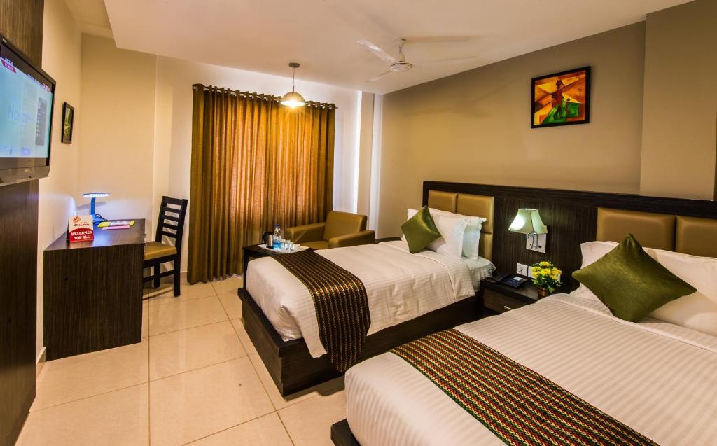 una camera d'albergo con due letti e una televisione di Plaza Hotel Trichy a Tiruchchirāppalli