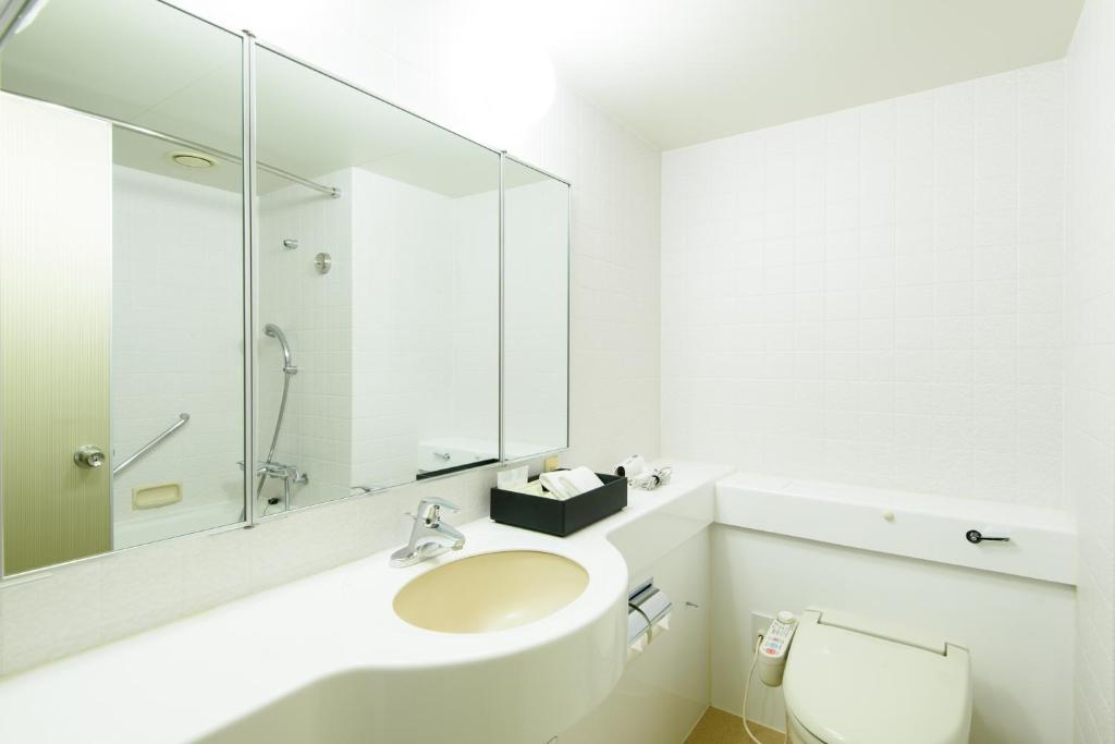a white bathroom with a sink and a mirror at Kanazawa Tokyu Hotel in Kanazawa
