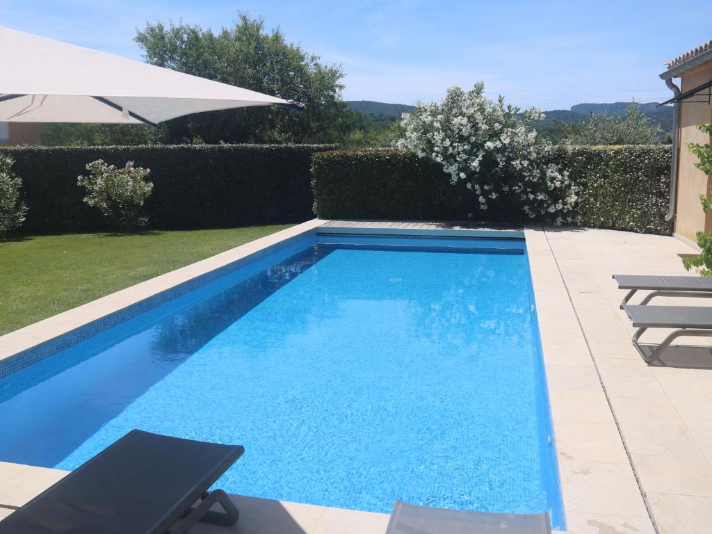 a swimming pool with two chairs and an umbrella at Luxury villa with private swimming pool in Malaucène