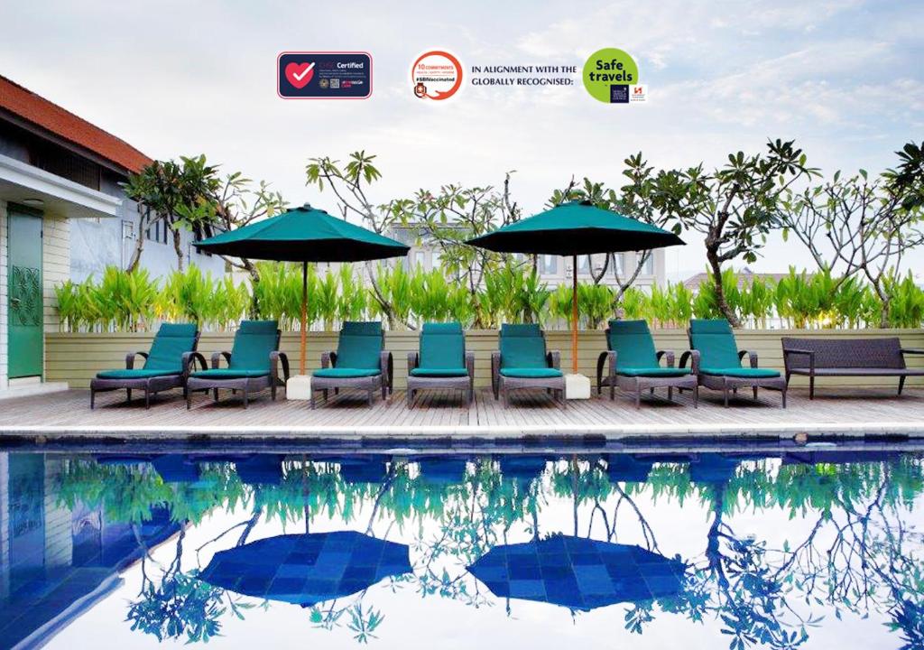 a group of chairs and umbrellas next to a swimming pool at Swiss-Belhotel Rainforest in Kuta