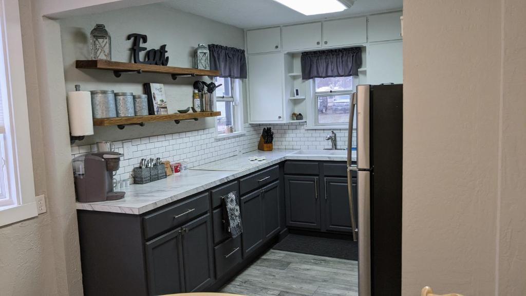 a kitchen with gray cabinets and a black refrigerator at The Cozy Idaho Gem 