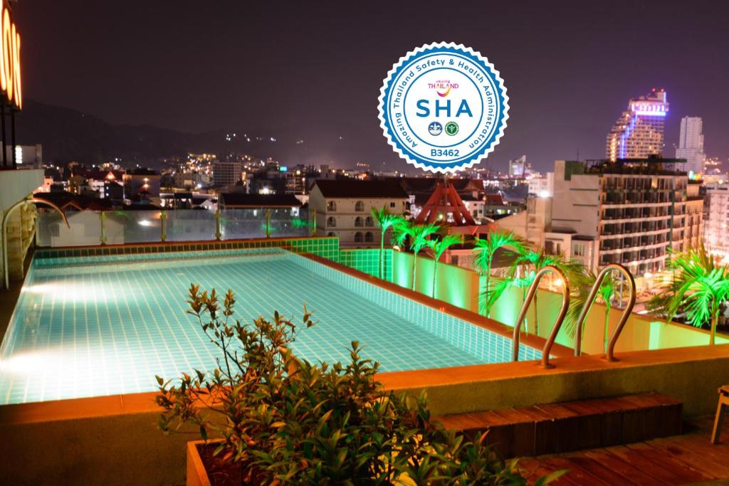 una piscina en la azotea de un edificio por la noche en Patong Mansion - SHA Certified, en Patong Beach