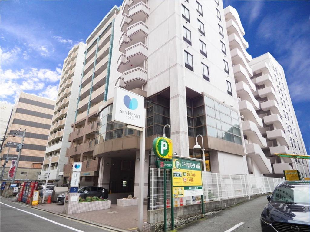 un gran edificio blanco con una señal de estacionamiento delante de él en Sky Heart Hotel Hakata, en Fukuoka