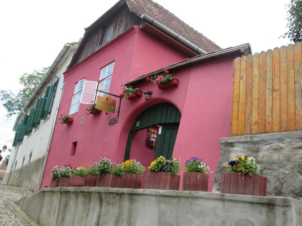 una casa rosa con macetas y una valla en Pensiunea Cristina si Pavel en Sighişoara