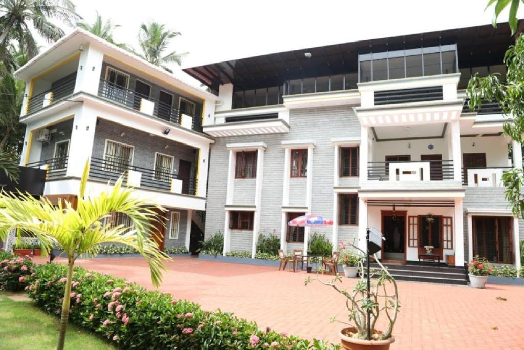 een groot wit gebouw met een binnenplaats ervoor bij Grace Homestay in Trivandrum