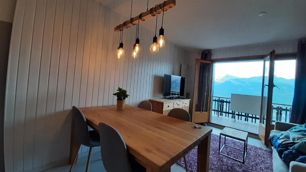 a dining room with a wooden table and a television at The purple fox's family home - Veysonnaz in Veysonnaz