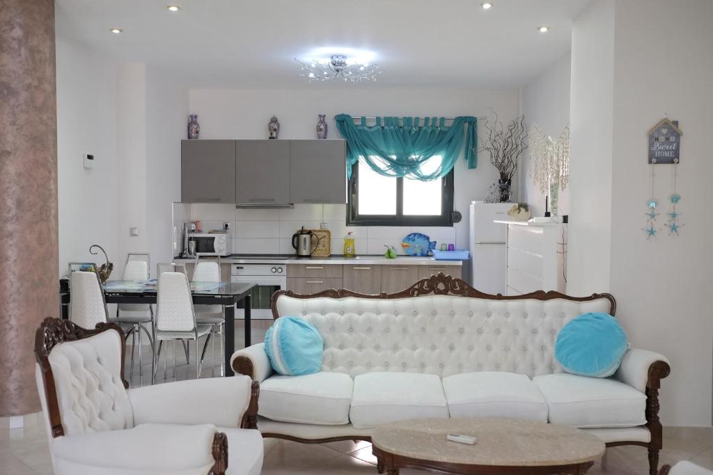 ein Wohnzimmer mit einem weißen Sofa und einer Küche in der Unterkunft Irenes Apartment in Kallithea (Chalkidiki)