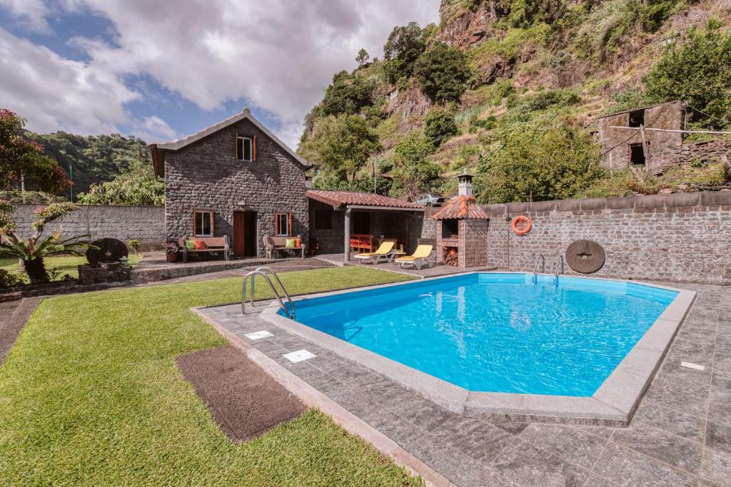 a pool in the yard of a stone house at Casa da Pedra in Santana