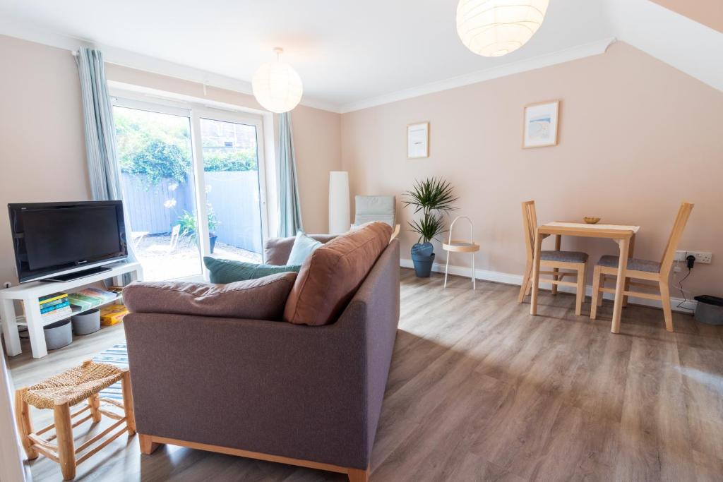 a living room with a couch and a television at Cosy Brixham apartment with garden close to Town in Brixham