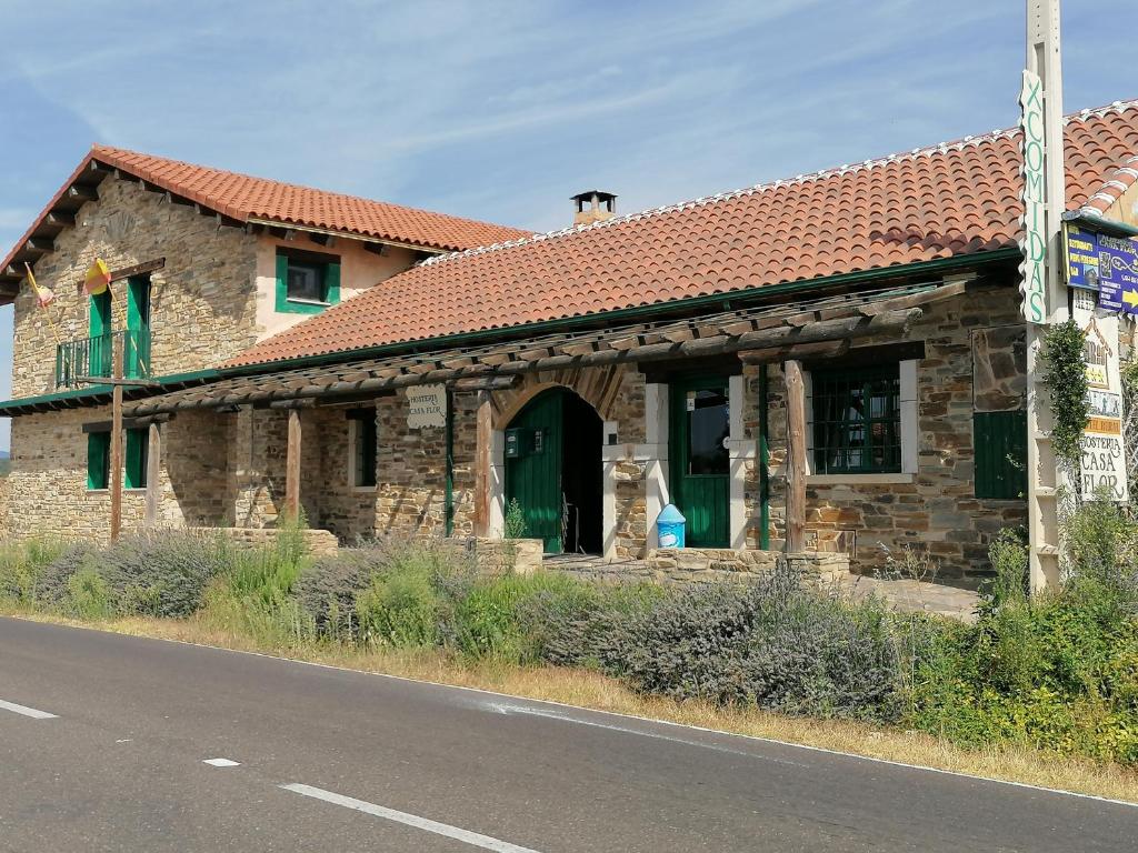 een stenen gebouw met een rood dak en groene deuren bij Hostería Casa Flor in Murias de Rechivaldo