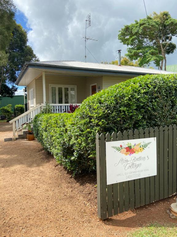 a house with a sign in front of a fence at Miss Bullens Cottage in Yungaburra