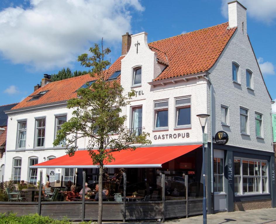 a white building with a red awning on a street at The Town hotel studios appartments in Zuidzande