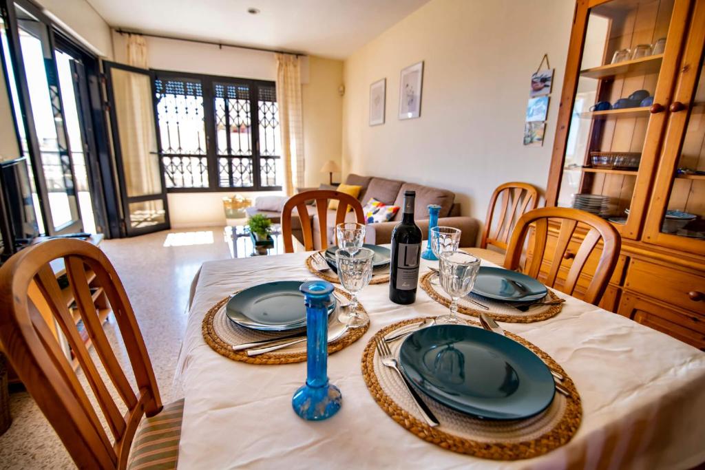 a dining room with a table with plates and wine glasses at Alquilaencanarias- Medano spectacular terrace and sea views B in El Médano