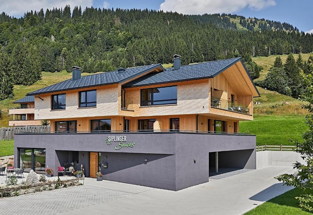 una casa grande con una montaña en el fondo en Siplinger Suites - Ferienwohnungen - Sauna und Fitness, en Balderschwang